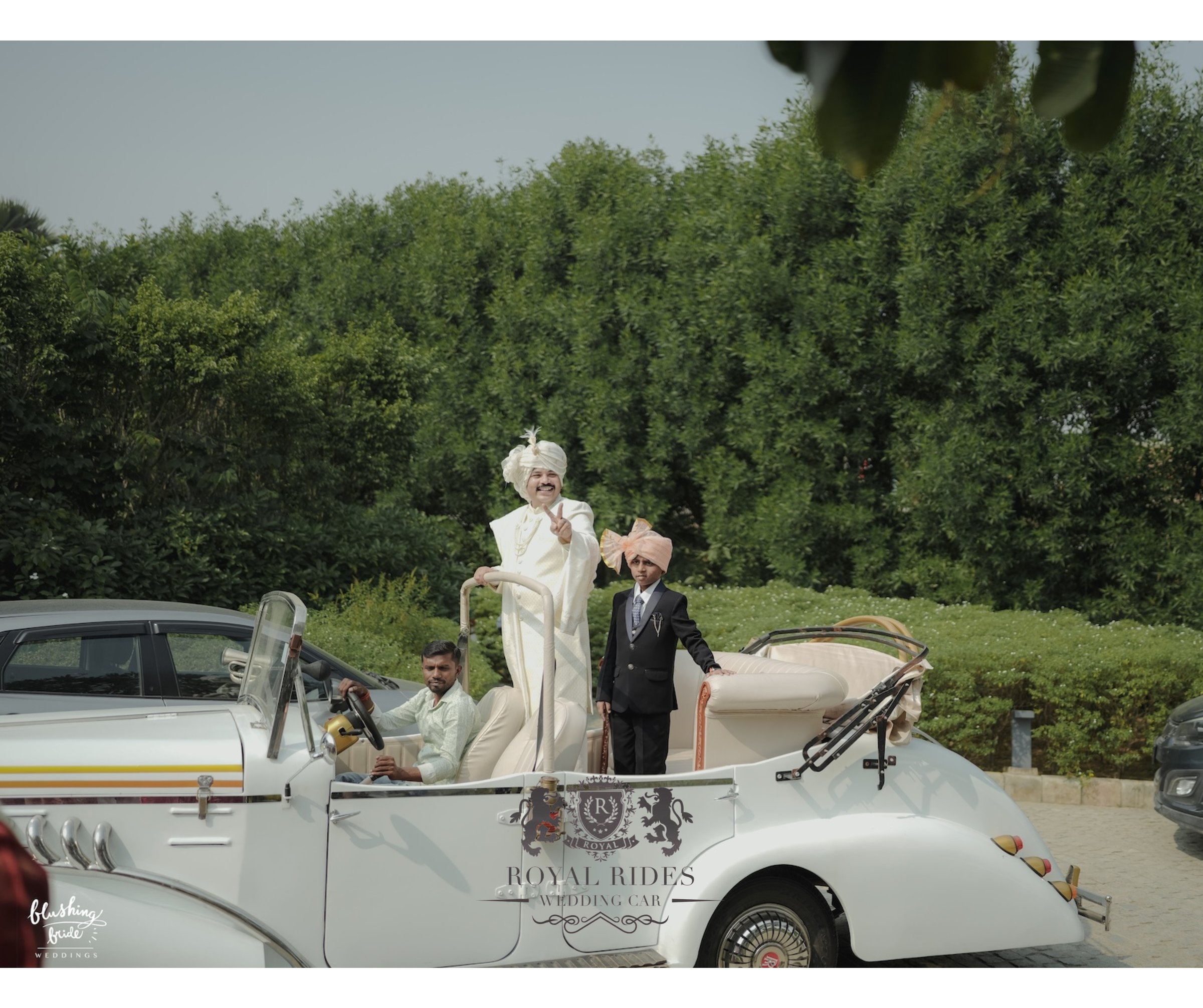 Groom standing in the open-top white vintage car during his baraat entry