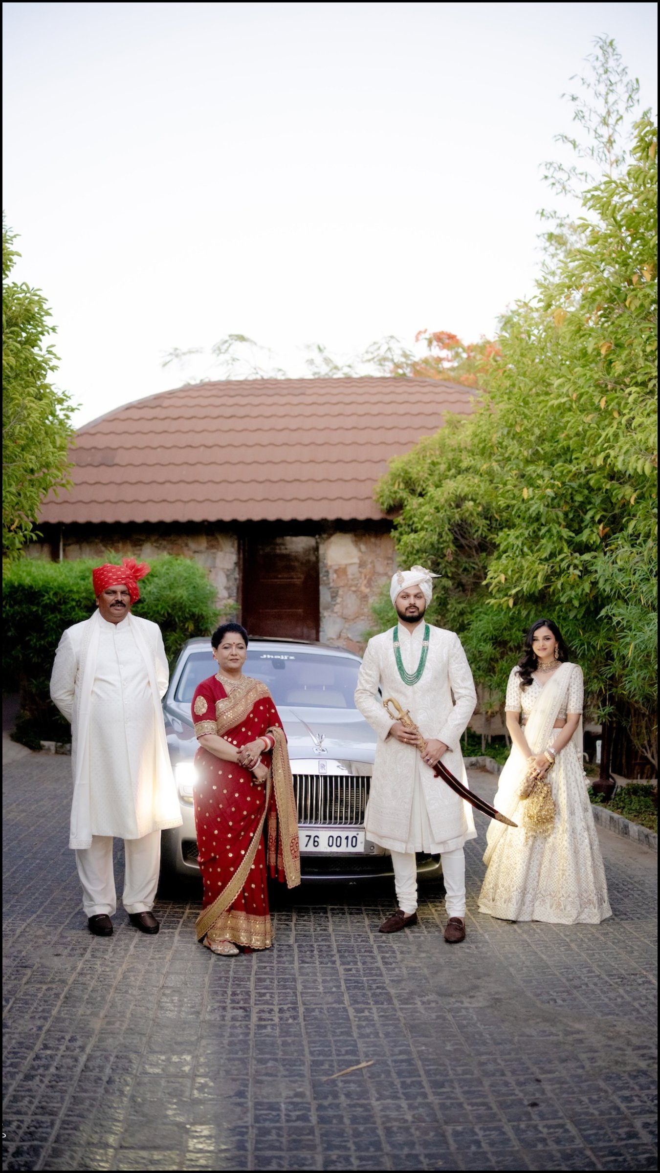 Groom with his parents and bride beside the wedding car