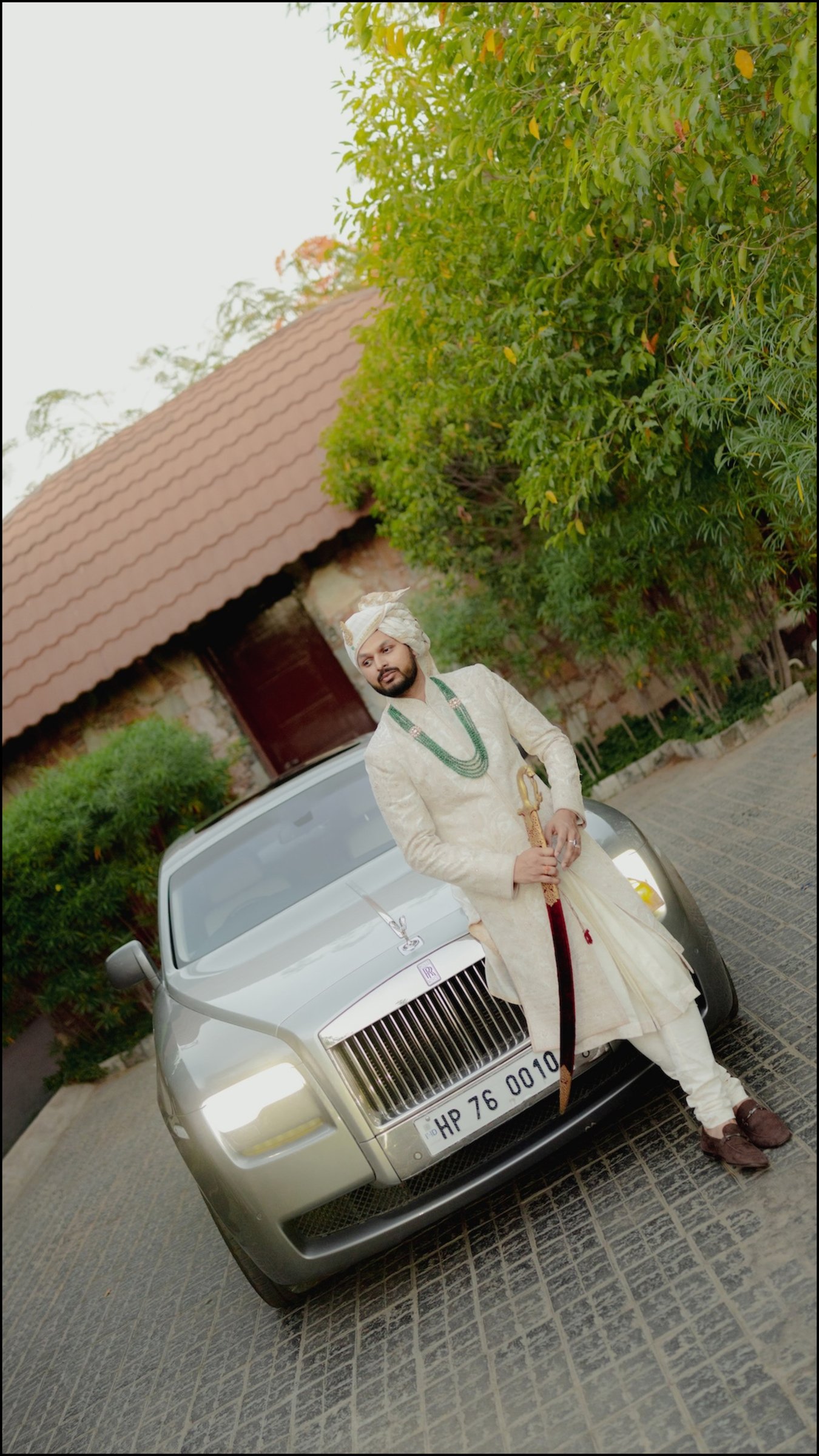 Groom posing on the bonnet of a silver luxury wedding car in Patna