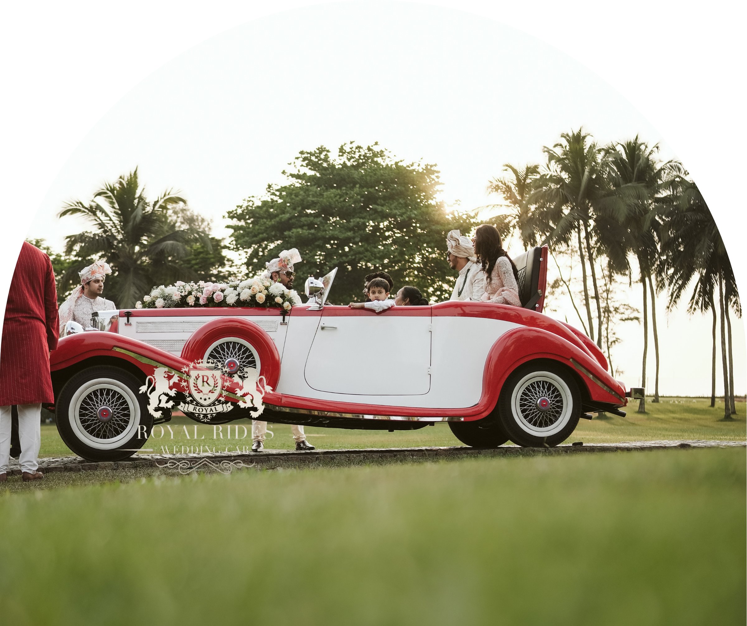 Red and white vintage convertible decorated with flowers on a wedding lawn